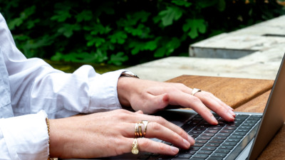 Handen op laptop met telefoon ernaast