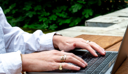 Handen op laptop met telefoon ernaast