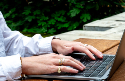 Handen op laptop met telefoon ernaast